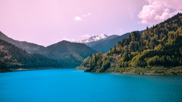 Lago rodeado de montañas y vegetación, con cielo despejado